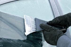 Winter driving scraping ice from windscreen